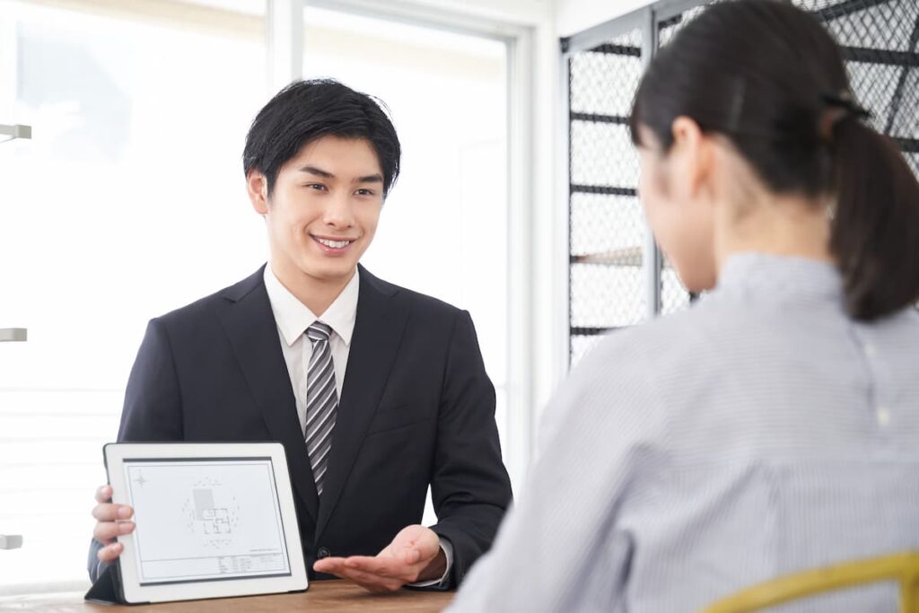タブレットで間取り図を見せながら説明する不動産会社の担当者