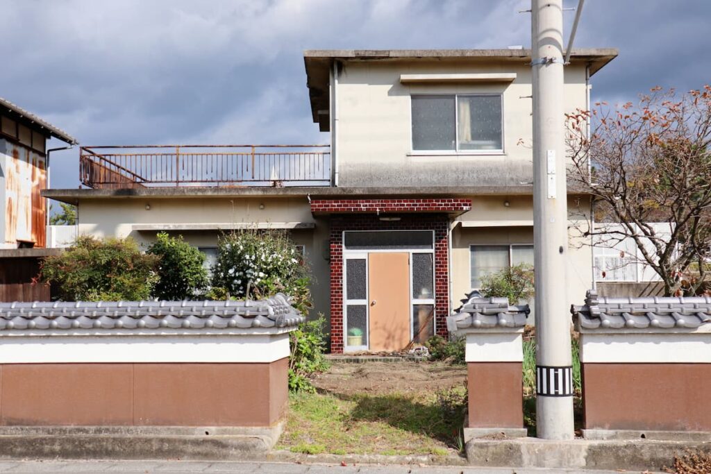 塀に囲まれた築年数の経過した戸建て住宅
