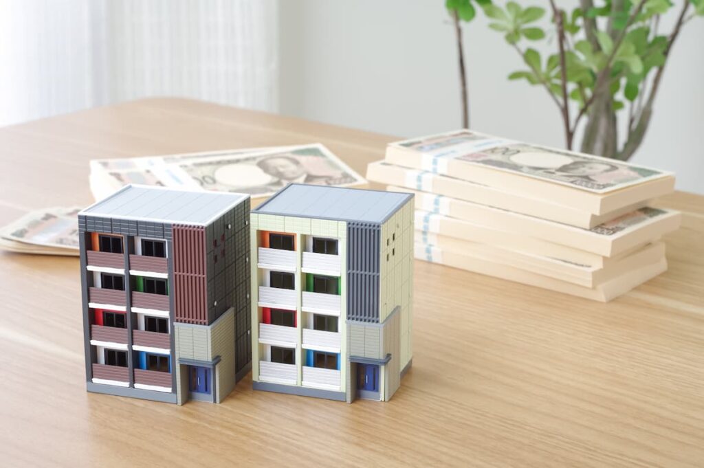 マンションの模型と積み重ねられた紙幣