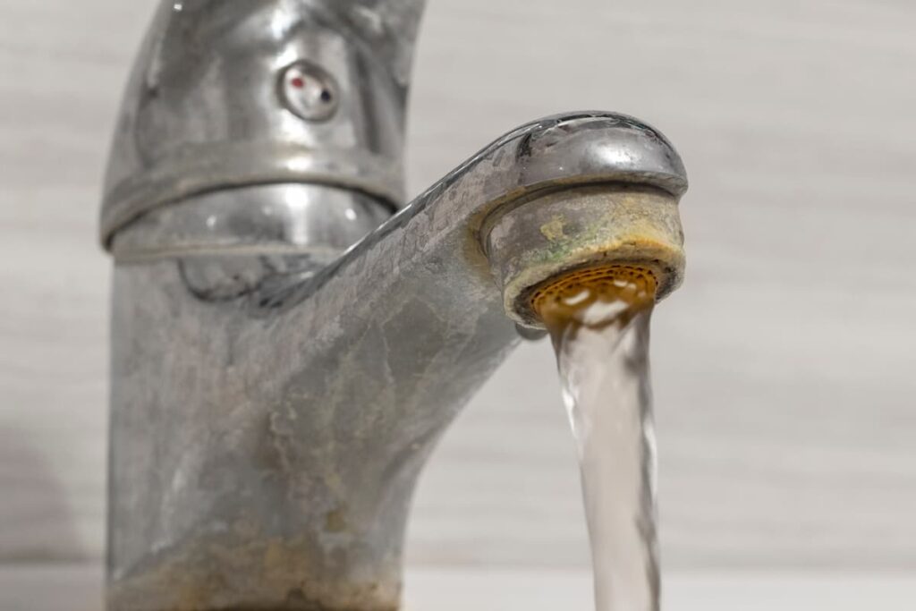 さびや汚れが付着した蛇口から流れる水