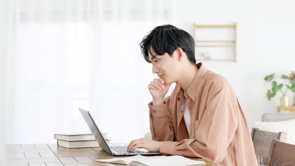 自宅でノートパソコンを使って物件情報を調べる男性