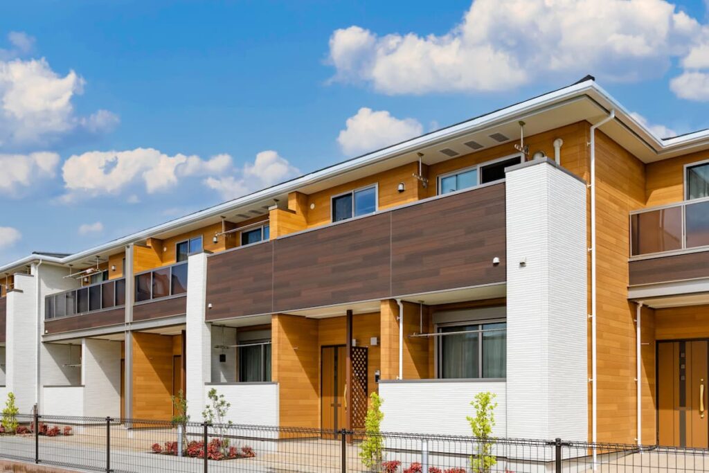 青空の下に並ぶ木目調の集合住宅