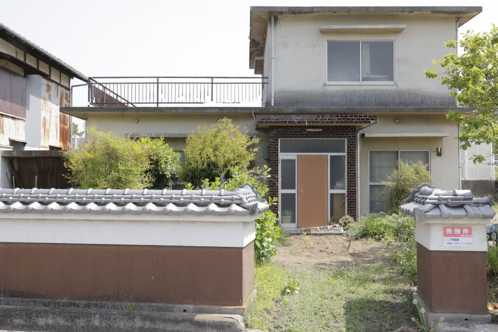 売物件の看板が掲げられた古い戸建て住宅
