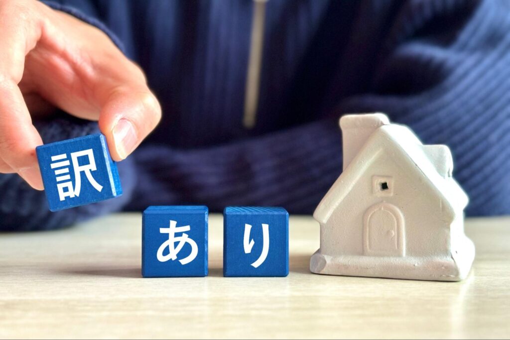 訳ありと書かれたブロックと住宅模型