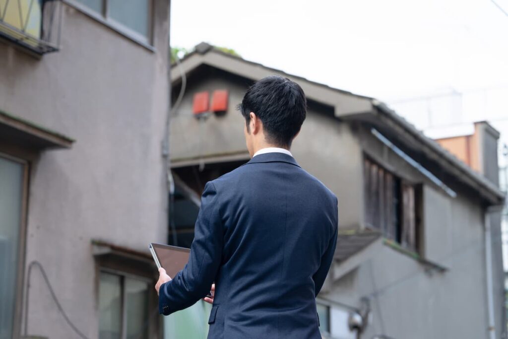 タブレットを持って古い住宅を調査する男性