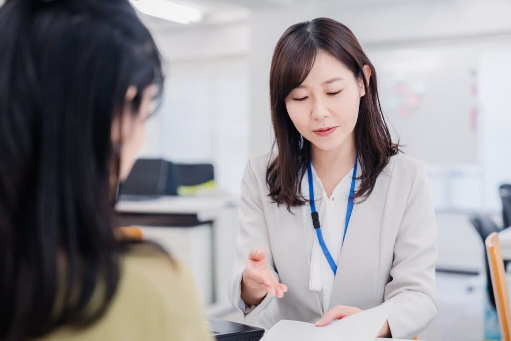 書類を見せながら相談者に説明する女性スタッフ