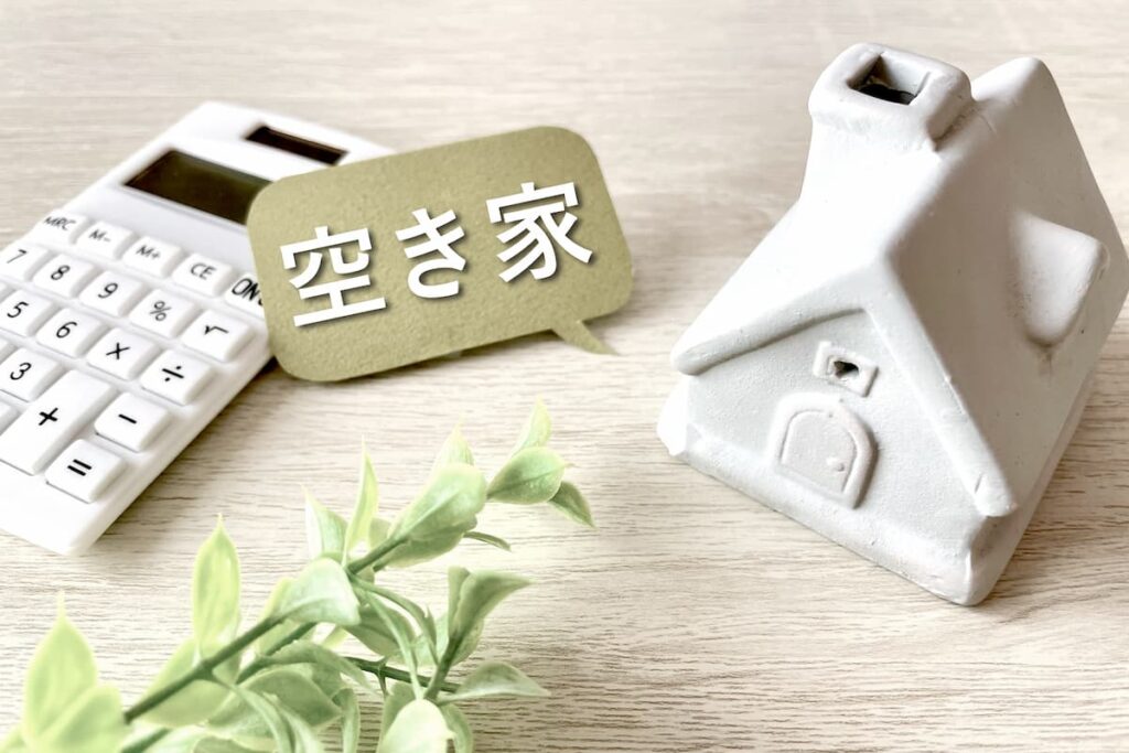 空き家と書かれた札、住宅模型、電卓