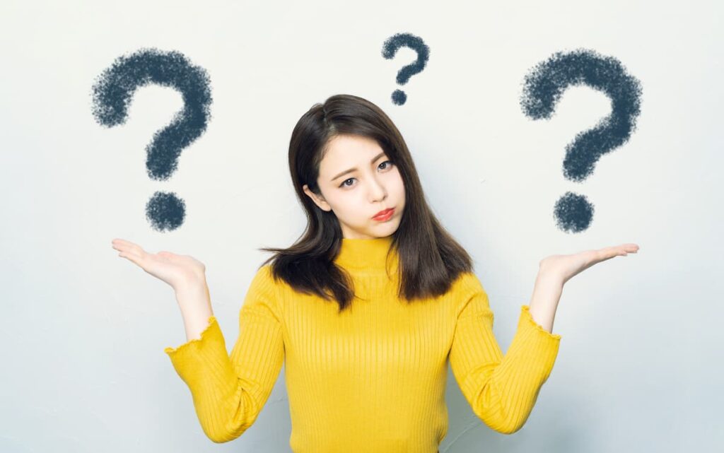 疑問符を背景に両手を広げて迷う女性