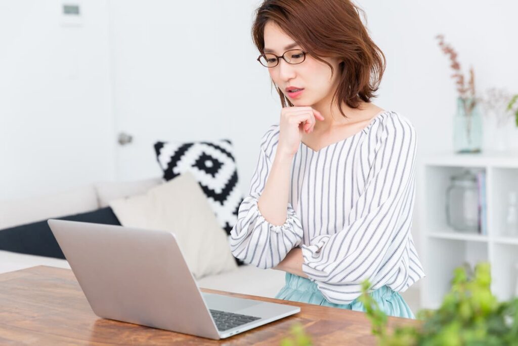 自宅でノートパソコンを使って物件情報を調べる女性