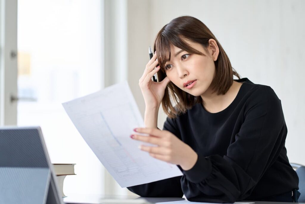 書類を確認しながら悩む女性