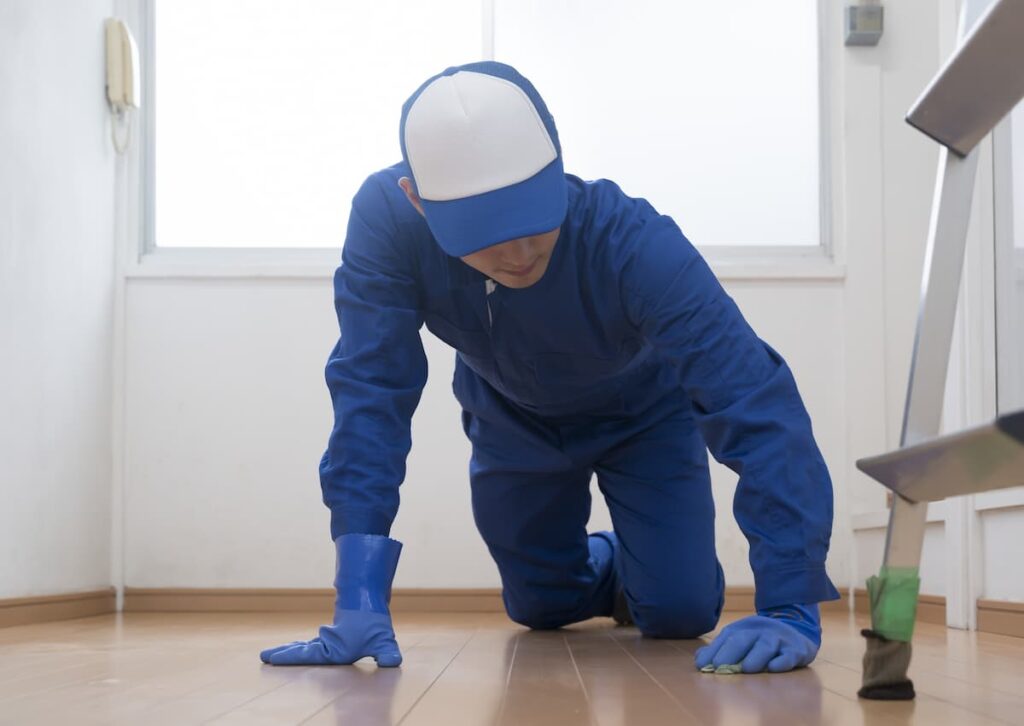 室内の床の状態を確認する作業員